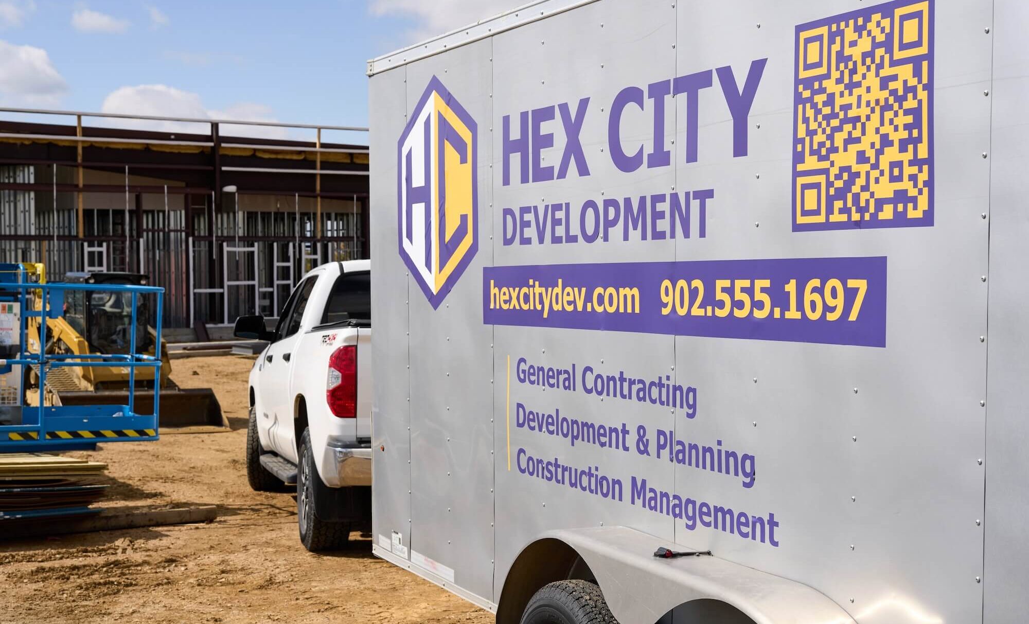 Hex City Development trailer with QR code, website hexcitydev.com, phone 902.555.1697, and service details at construction site