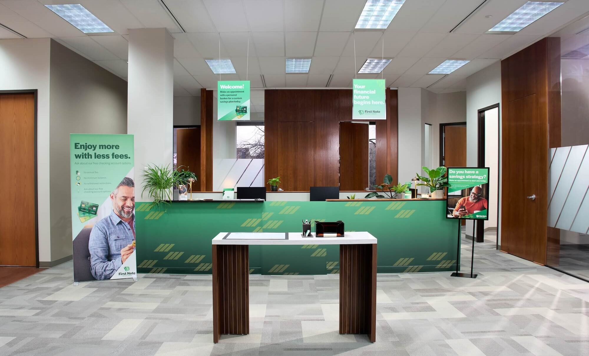 Bank lobby with green-themed design, promotional banners, and "First Note" signage.