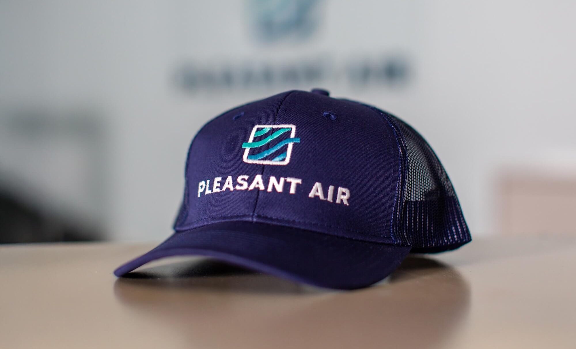 Blue cap with the "Pleasant Air" logo embroidered on the front.